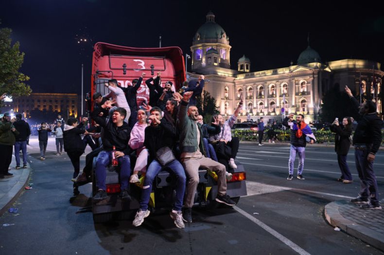 Personas celebran frente a la Asamblea Nacional luego que Aleksandar Vučić, líder del partido de derecha Partido Progresista Serbio (SNS), reconociera su derrota en las elecciones parlamentarias en Belgrado, Serbia, la madrugada del lunes 26 de octubre de 2026. (Foto AP/Armin Durgut)
