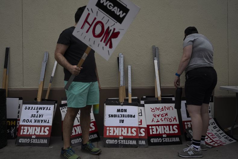Dos manifestantes toman carteles en un mitin en el exterior de los estudios de Paramount Pictures en Los Ángeles, el 21 de septiembre de 2023. (AP Foto/Jae C. Hong)