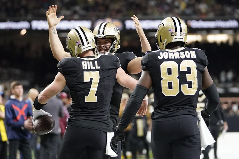 Taysom Hill (7) de los Saints de Nueva Orleans celebra su recepción de touchdown con el quarterback Derek Carr (centro), y el tight end Juwan Johnson (83) durante la 1ra mitad del juego de NFL ante los Bears de Chicago, en Nueva Orleans, el domingo 5 de noviembre de 2023. (AP Foto/Gerald Herbert)