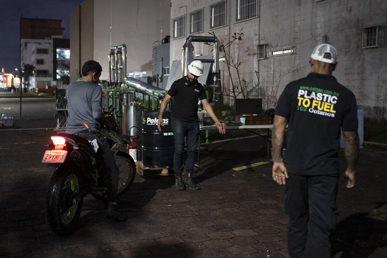 Carlos Parraguirre Díaz and Jesús Cuevas bombean gasolina de Petgas, fabricada a partir de residuos plásticos, a una motocicleta, en Boca del Río, en el estado de Veracruz, México, el 4 de enero de 2025. (AP Foto/Félix Márquez)