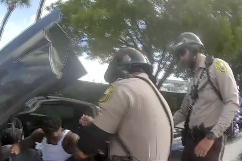 Esta imagen, tomada por la cámara que un agente llevaba ceñida al cuerpo, muestra a otro policía, que saca de su vehículo a Tyreek Hill, receptor de los Dolphins de Miami, el domingo 8 de septiembre de 2024 (Miami-Dade Police Department)