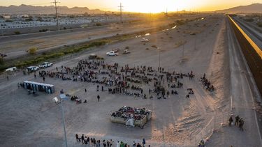 A medida que el sol se pone, migrantes aguardan afuera de una puerta en la cerca fronteriza el jueves 11 de mayo de 2023 para ingresar a El Paso, Texas, con el fin de que la Patrulla Fronteriza procese sus casos. Gran cantidad de migrantes se apresuraron a cruzar la frontera con México, en un intento apresurado por ingresar a Estados Unidos antes de que llegara a su fin una norma que restringía el asilo, en un cambio de política que amenaza con agobiar aún más el sistema migratorio de Estados Unidos. (AP Foto/Andrés Leighton)