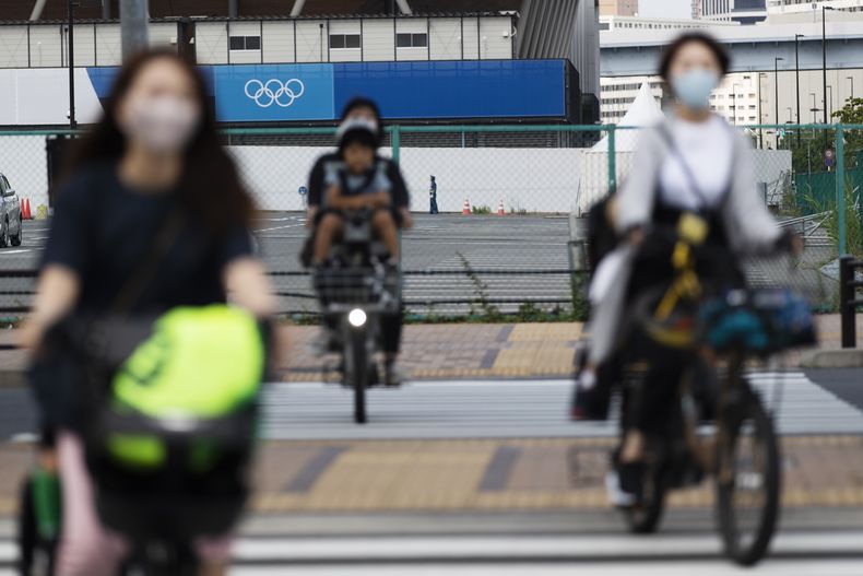 ARCHIVO - Mujeres llevan a sus hijos en sus bicicletas mientras se dirigen a una intersección cerca de una arena deportiva planeada para usarse durante los Juegos Olímpicos y Paralímpicos de Tokio 2020, el 24 de junio de 2021. (AP Foto/Hiro Komae, archivo)