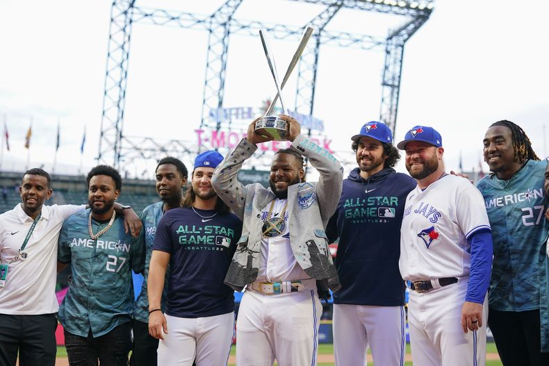 Vladimir Guerrero Jr., de los Azulejos de Toronto, alza el trofeo que lo acredita como campeón del Derby de Jonrones, rodeado de sus compañeros después de ganar la competencia, en Seattle, el lunes 10 de julio de 2023. (AP Foto/Lindsey Wasson)