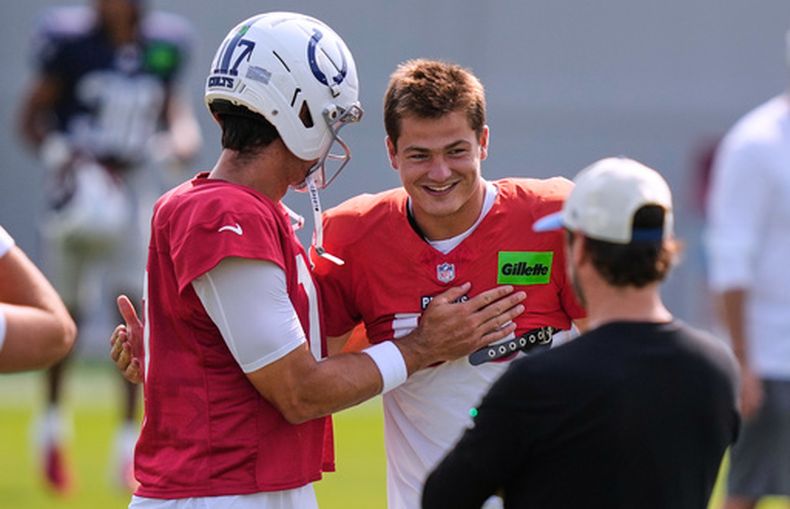 El quarterback de los Patriots de Nueva Inglaterra, Drake Maye (derecha), saluda al quarterback de los Colts de Indianápolis, Daniel Jones (17), antes de una sesión de práctica conjunta en un campamento de entrenamiento de fútbol americano de la NFL en Foxborough, Massachusetts, el martes 11 de agosto de 2026. (Foto AP/Charles Krupa)