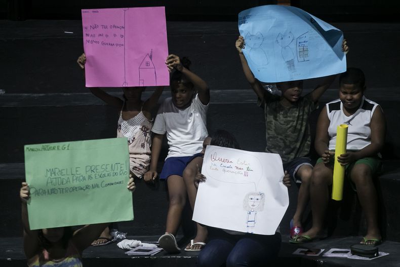 Unos niños sostienen dibujos que representan sus experiencias de vida en la favela Maré durante la presentación del libro titulado Se suponía que tenía que estar en la escuela en la favela Maré de Río de Janeiro, Brasil, el lunes 25 de marzo de 2024. (AP Foto/Bruna Prado)