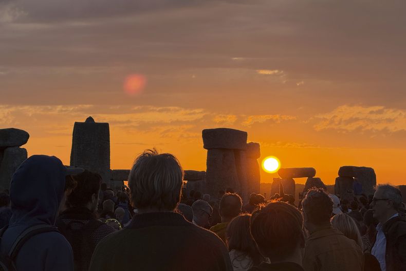 Varias personas observan el amanecer en Stonehenge, Inglaterra, durante el solsticio de verano, el sábado 21 de junio de 2025. (Zhanna Manukyan/PA vía AP)