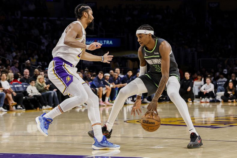 El jugador de los Timberwolves de Minnesota Jaden McDaniels (3) elude al jugador de los Lakers de Los Ángeles Spencer Dinwiddie (26) en la primera mitad de su juego de NBA el domingo 7 de abril de 2024, en Los Ángeles. (AP Foto/Etienne Laurent)