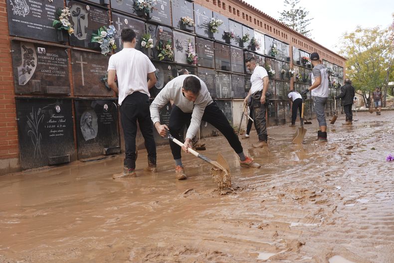 Gente retira lodo de un cementerio dañado por inundaciones a las afueras de Valencia, España, el viernes 1 de noviembre de 2024 después de inundaciones en la región. (AP Foto/Alberto Saiz)