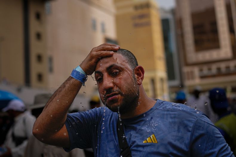 Un peregrino musulmán se echa agua sobre la cabeza para refrescarse ante la Gran Mezquita durante el peregrinaje anual del haj en la ciudad sagrada de La Meca, en Arabia Saudí, el domingo 24 de mayo de 2026. (AP Foto/Altaf Qadri)