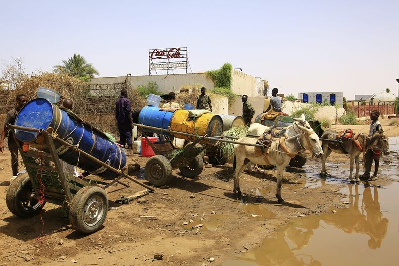 Gente llena contenedores de agua en un punto de distribución establecido por falta de agua en Jartum, Sudán, en domingo 25 de mayo de 2025. (AP Foto)