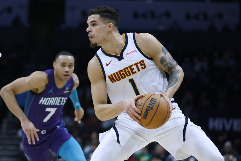 Michael Porter Jr., alero de los Nuggets de Denver, busca disparar frente a Bryce McGowens, de los Hornets de Charlotte, en el encuentro del sábado 23 de diciembre de 2023 (AP Foto/Nell Redmond)