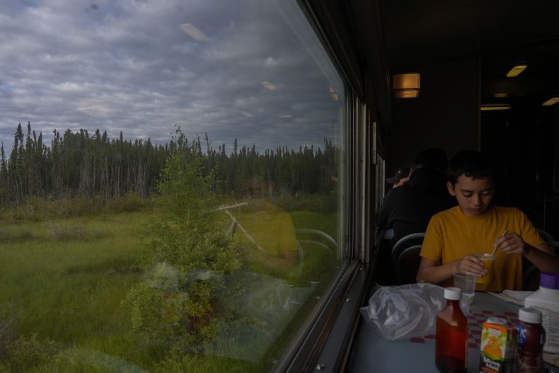 Un pasajero come mientras viaja en tren, el viernes 9 de agosto de 2024, cerca de Ilford, Manitoba. (AP Foto/Joshua A. Bickel)
