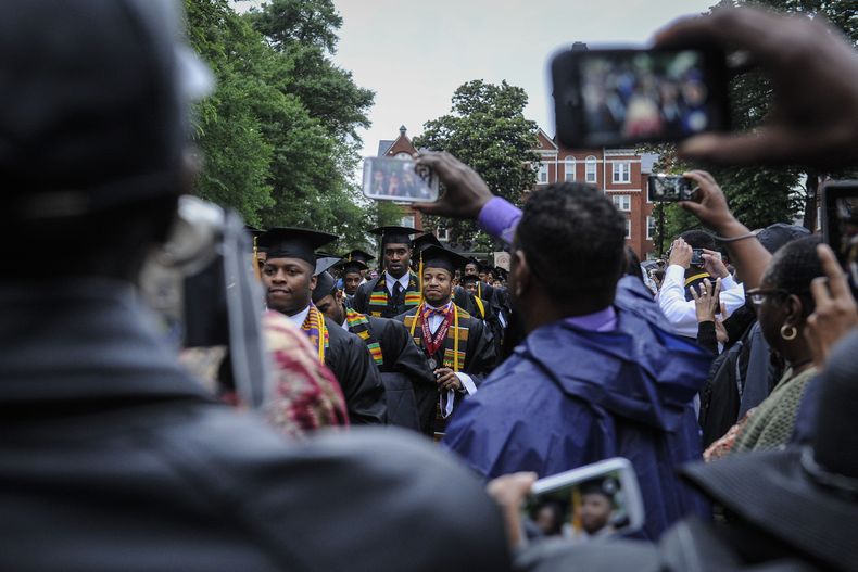 ARCHIVO – Los graduados del Morehouse College desfilan frente a las cámaras de los teléfonos al llegar a la ceremonia de graduación en el campus, el 18 de mayo de 2014, en Atlanta. (John Amis/Atlanta Journal-Constitution vía AP, Archivo)