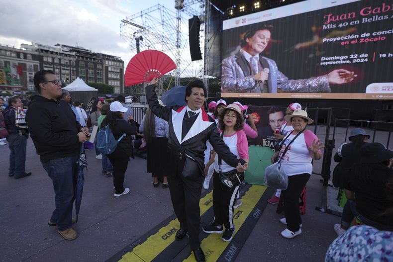 Jhoanfa El Espejo de Juan Gabriel, un imitador del fallecido astro mexicano Juan Gabriel, actúa junto a un club de fans antes de la proyección de uno de los conciertos de Juan Gabriel en el Zócalo, la plaza principal de la Ciudad de México, el domingo 22 de septiembre de 2024.(Foto AP/Fernando Llano)