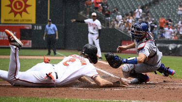 Gunnar Henderson de los Orioles de Baltimore se lanza al plato frente al catcher de Los Ángeles Austin Barnes tras el doble anotador del mexicano Ramón Urías en el encuentro del miércoles 19 de julio del 2023. (AP Foto/Nick Wass)