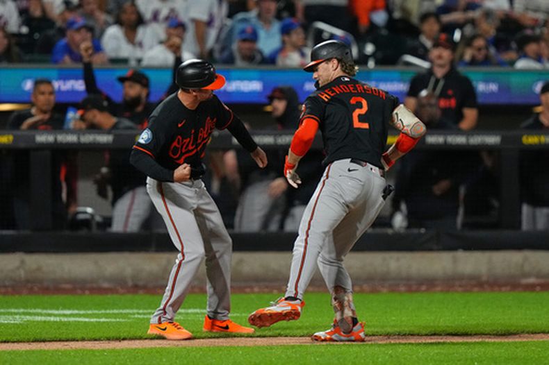 El coach de tercera de los Orioles de Baltimore, Buck Britton, izquierda, celebra con Gunnar Henderson, derecha, mientras el toletero corre las bases después de batear un jonrón durante la octava entrada del juego de béisbol de Grandes Ligas contra los Mets de Nueva York, el lunes 14 de septiembre de 2026, en Nueva York. (AP Foto/Frank Franklin II)