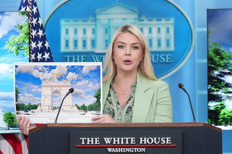 La secretaria de prensa de la Casa Blanca, Karoline Leavitt, sostiene una ilustración artística del nuevo arco del triunfo mientras habla con los periodistas en la Sala de Ruedas de Prensa James Brady de la Casa Blanca, el miércoles 15 de abril de 2026, en Washington. (Foto AP/Alex Brandon)