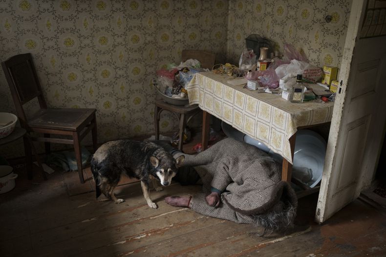 Un perro está parado junto al cuerpo de una mujer mayor que murió al interior de una casa en Bucha, en las afueras de Kiev, Ucrania, el martes 5 de abril de 2022. (AP Foto/Felipe Dana)