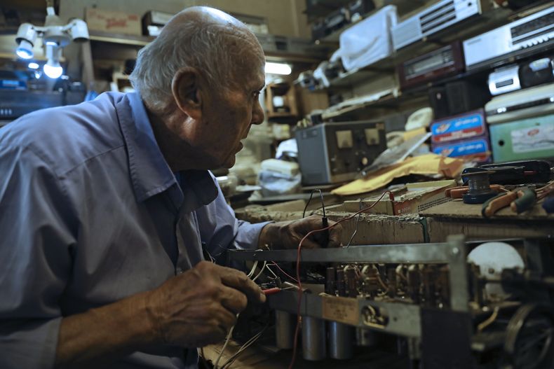 Reza Alimirzaei, de 73 años, que repara y vende radios viejas, trabaja en su tienda en el centro de Teherán, Irán, el miércoles 18 de septiembre de 2024. (Foto AP/Vahid Salemi)