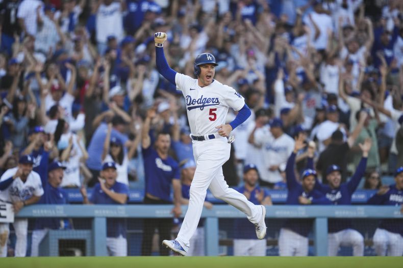 Freddie Freeman (5), de los Dodgers de Los Ángeles, festeja y anota después de que su compañero Will Smith (16) conectara un jonrón en la octava entrada del partido contra los Astros de Houston, en Los Ángeles, el domingo 25 de junio de 2023. Freeman logró en ese inning su hit 2.000. (AP Foto/Ashley Landis)