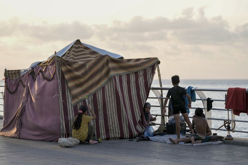 Una familia desplazada que huye de ataques aéreos israelíes en el sur se ve sentada junto a su carpa en Beirut, Líbano, el lunes 14 de octubre de 2024. (AP Foto/Bilal Hussein)