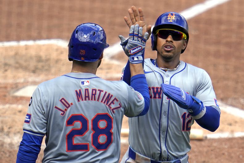 Francisco Lindor (12), de los Mets de Nueva York, es felicitado por J.D. Martinez (28) al regresar rumbo al dugout después de anotar con un doble de Brandon Nimmo ante el relevista de los Piratas de Pittsburgh Colin Holderman durante la octava entrada del juego de béisbol del domingo 7 de julio de 2024. (AP Foto/Gene J. Puskar)