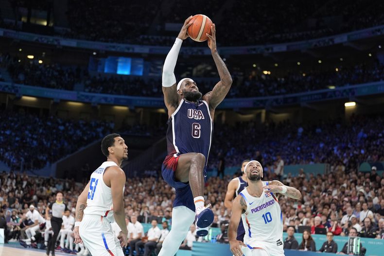 El estadounidense LeBron James (6) se eleva para una volcada en el partido contra Puerto Rico en el baloncesto de los Juegos Olímpicos de París, el sábado 3 de agosto de 2024, en Villeneuve-dAscq, Francia. (AP Foto/Michael Conroy)