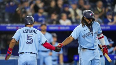 Santiago Espinal (5) de los Azulejos de Toronto celebra con su compañero Vladimir Guerrero Jr. (27) tras anotar una carrera ante los Medias Blancas de Chicago, el miércoles 26 de abril de 2023, en Toronto. (Andrew Lahodynskyj/The Canadian Press vía AP)