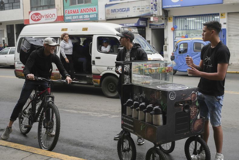 Maikol Gámez llega con su bicicleta para unirse a sus hermanos Darling y Jhonier en la venta callejera de café en Lima, Perú, el viernes 23 de agosto de 2024. (AP Foto/Guadalupe Pardo)