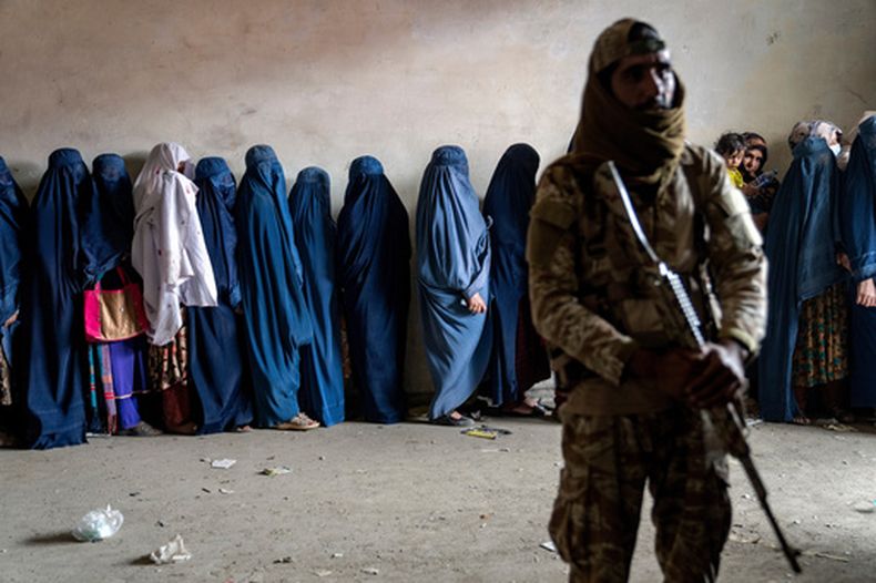 ARCHIVO – Un combatiente talibán monta guardia mientras varias mujeres esperan para recibir raciones de alimentos distribuidas por un grupo de ayuda humanitaria en Kabul, Afganistán, el martes 23 de mayo de 2023. (AP Foto/Ebrahim Noroozi, Archivo)