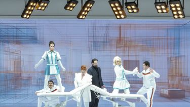 El barítono Edward Parks (centro) hace el papel de Don Alfonso, el CEO de una empresa de inteligencia artificial, en una escena de la producción de Cosi fan tutte de Mozart hecha por Yuval Sharon, en la Ópera de Detroit. (Austin T. Richey/Ópera de Detroit via AP)