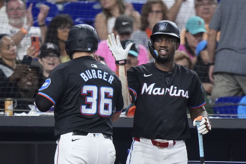 Jake Burger (36), de los Marlins de Miami, es felicitado por su compañero Jesús Sánchez después de que Burger anotara con sencillo de Josh Bell durante la tercera entrada del juego de béisbol en contra de los Mets de Nueva York, el viernes 19 de julio de 2024, en Miami. (AP Foto/Wilfredo Lee)