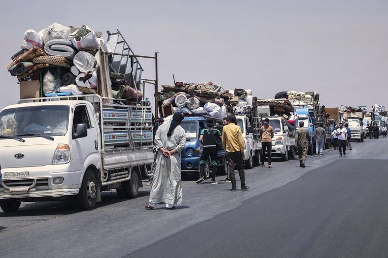 Camiones con cerca de 60 familias desplazadas se reúnen de camino al poblado de Kafr Sijna después de pasar más de cinco años en los campos de Atmeh, cerca de la frontera siria con Turquía, en una autopista en el norte de Kafr Sijna, Siria, el domingo 18 de marzo de 2025. (AP Foto/Ghaith Alsayed)