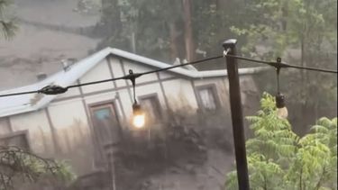 En esta imagen tomada de un video, una casa es arrastrada por una crecida tras una casa en Ruidoso, Nuevo México, el martes 8 de julio de 2025. (Kaitlyn Carpenter via AP)