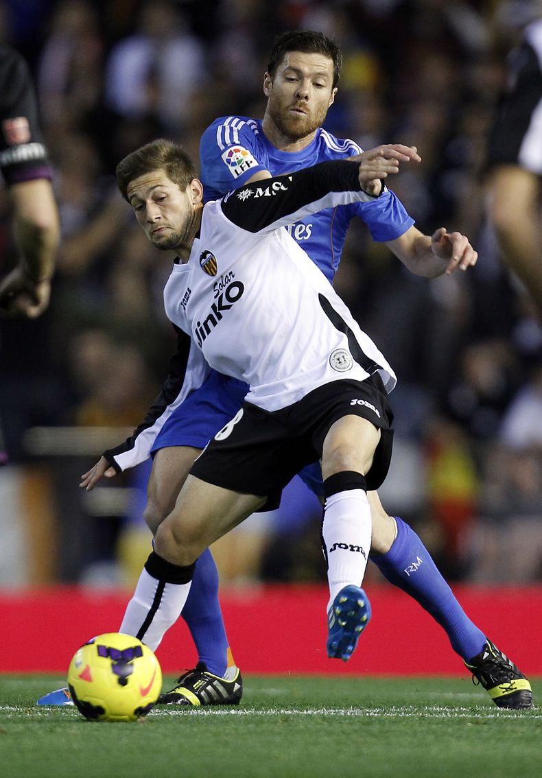 El volante de Real Madrid Xabi Alonso disputa un bal&oacute;n con Fede Cartabia, de Valencia (en primer plano) durante el partido que el equipo merengue gan&oacute; 3-2 el 22 de diciembre del 2013 en Valencia. Alonso sufri&oacute; la perforaci&oacute;n de