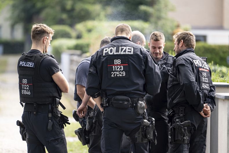Agentes de policía coordinan la búsqueda de un animal salvaje huido en una zona residencial en Teltow, Alemania, el 20 de julio de 2023. (Fabian Sommer/dpa vía AP)