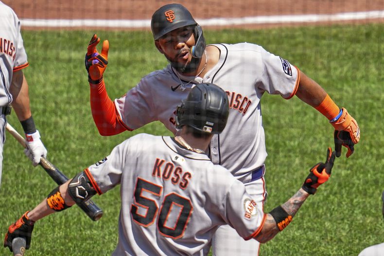 Jerar Encarnacion, de los Gigantes de San Francisco, arriba, celebra con Christian Koss (50) mientras regresa al dugout después de conectar un jonrón solitario contra el lanzador de los Piratas de Pittsburgh, Andrew Heaney, durante la quinta entrada de un partido de béisbol en Pittsburgh, el miércoles 6 de agosto de 2025. (AP Photo/Gene J. Puskar)