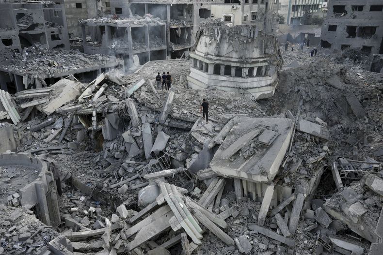 Palestinos inspeccionan los escombros de la mezquita de Yassin, destruida por un ataque aéreo israelí, en el campo de refugiados de Shati, en la Ciudad de Gaza, el 9 de octubre de 2023. (AP Foto/Adel Hana)