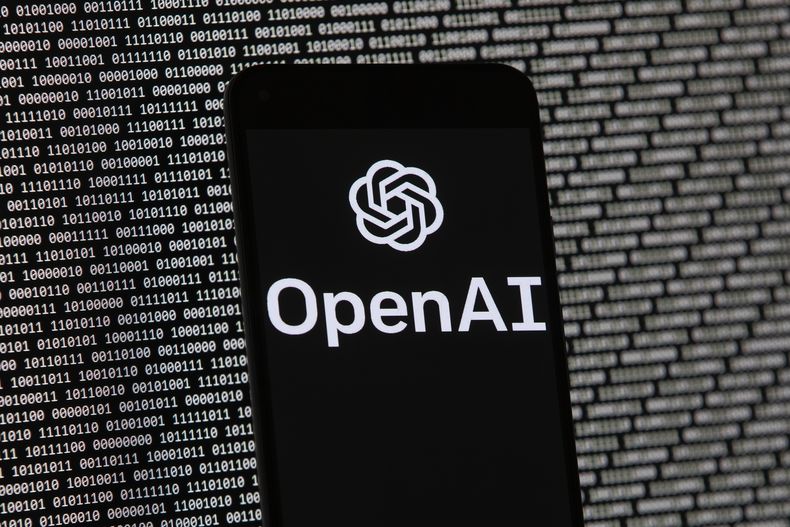ARCHIVO - El logotipo de OpenAI aparece en un teléfono celular frente a la pantalla de una computadora, el 9 de marzo de 2023, en Boston. (AP Foto/Michael Dwyer, archivo)