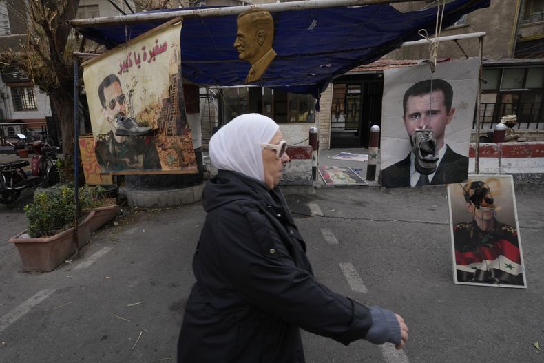 Zapatos colgados frente a retratos del depuesto presidente sirio Bashar Assad en Damasco, Siria, lunes 23 de diciembre de 2024. (AP foto/Hussein Malla)