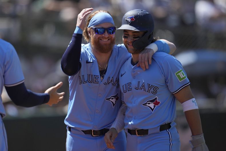 Justin Turner, izquierda, de los Azulejos de Toronto, celebra con Bo Bichette después de que ambos anotaran con doble productor de tres carreras de Isiah Kiner-Falefa durante la 10ma entrada en el juego contra los Atléticos de Oakland, en Oakland, California, el domingo 9 de junio de 2024. (AP Foto/Jeff Chiu)
