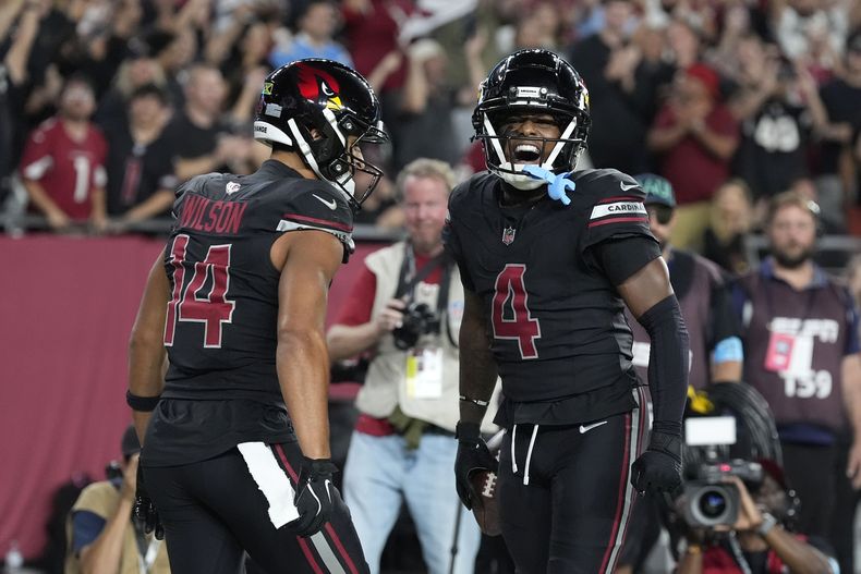 El wide receiver de los Cardinals de Arizona Greg Dortch (4) celebra con su compañero de equipo Michael Wilson (14) después de atrapar un pase de touchdown de 5 yardas durante la primera mitad de un partido contra los Chargers de Los Ángeles, el lunes 21 de octubre de 2024, en Glendale, Arizona (AP Foto/Ross D. Franklin)