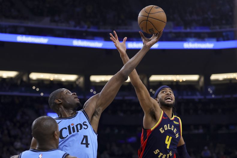 Mo Bamba, izquierda, de los Clippers de Los Ángeles, y Moses Moody, de los Warriors de Golden State, disputan un balón en lo alto durante la primera mitad del juego de baloncesto de la NBA, el viernes 27 de diciembre de 2024, en Inglewood, California. (AP Foto/Ryan Sun)