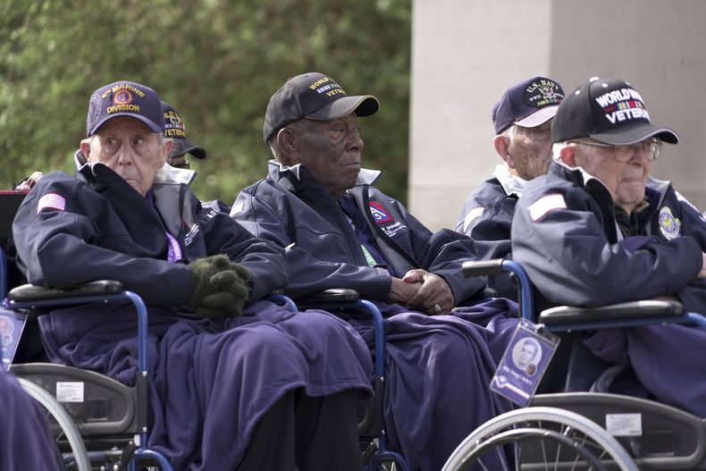Calvin Shiner (centro), de 102 años y que fue seleccionado en 1943 para ingresar en una unidad de construcción de soldados negros en el ejército de Estados Unidos, y otros veteranos de la Segunda Guerra Mundial, asisten a un acto de conmemoración el 2 de junio de 2025 en Colleville-sur-Mer, en el cementerio estadounidense de Normandía, en vísperas del aniversario del Día D. (AP Foto/John Leicester)