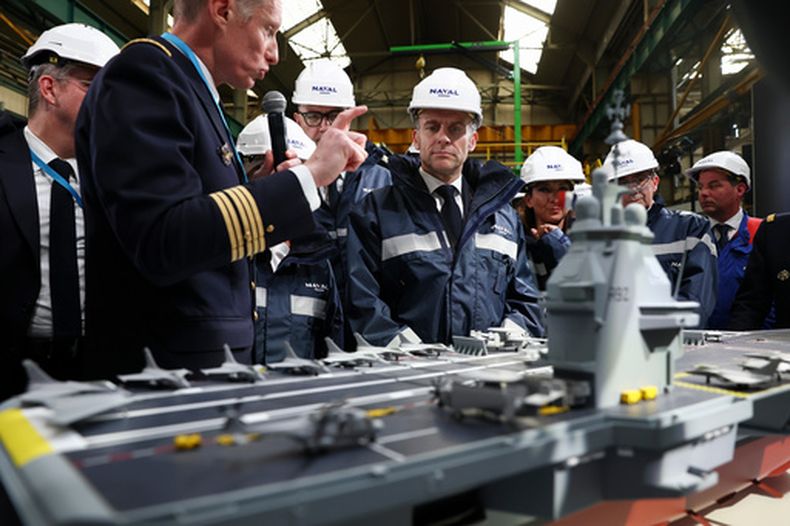 El presidente francés Emmanuel Macron, centro, junto al modelo de un buque llamado France Libre (“Francia Libre”), durante su visita al sitio de construcción de Naval Group Nantes-Indret, donde se construye el portaaviones francés de próxima generación, en Indret, Francia, el miércoles 18 de marzo de 2026. (Gonzalo Fuentes/Pool Foto vía AP)