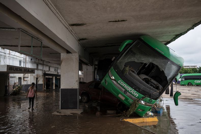 Una mujer camina el sábado 11 de octubre de 2025 por una estación de autobuses dañada tras las fuertes lluvias caídas en Poza Rica, en el estado de Veracruz, México. (AP Foto/Félix Márquez)
