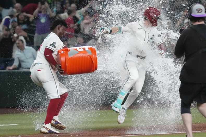 Corbin Carroll, derecha, de los Diamondbacks de Arizona, recibe un baño de Geraldo Perdomo después de batear un cuadrangular de dos carreras decisivo frente a los Marlins de Miami en la novena entrada, el lunes 14 de septiembre de 2026, en Phoenix. (AP Foto/Rick Scuteri)