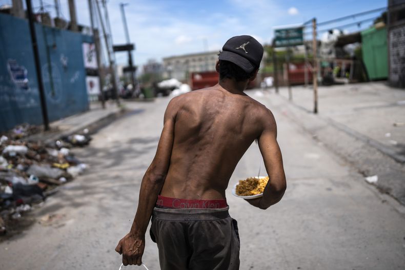 Nicolás Gonzáles camina con un plato de comida a la salida de la Casa Comunitaria del Fondo en el barrio Padre Carlos Múgica de Buenos Aires, Argentina, el miércoles 13 de de diciembre de 2023. El gobierno argentino eliminó subsidios al transporte y energía y devaluó el peso a más de la mitad, de 400 a 800 pesos por dólar, como parte de las medidas de ajuste que el nuevo presidente, Javier Milei, defiende ante las urgencias económicas del país. (AP Foto/Rodrigo Abd)