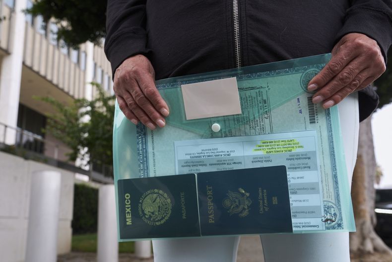 Margarita Vélez, madre de Andrea Vélez, ciudadana estadounidense del sur de Los Ángeles, sostiene el pasaporte estadounidense actual de su hija y su pasaporte mexicano, mientras busca su ubicación, luego de que agentes de ICE detuvieran a Andrea Vélez durante una redada de inmigración en el centro, afuera del Centro de Detención Metropolitano en Los Ángeles el miércoles 25 de junio de 2025. (Foto AP/Damian Dovarganes)
